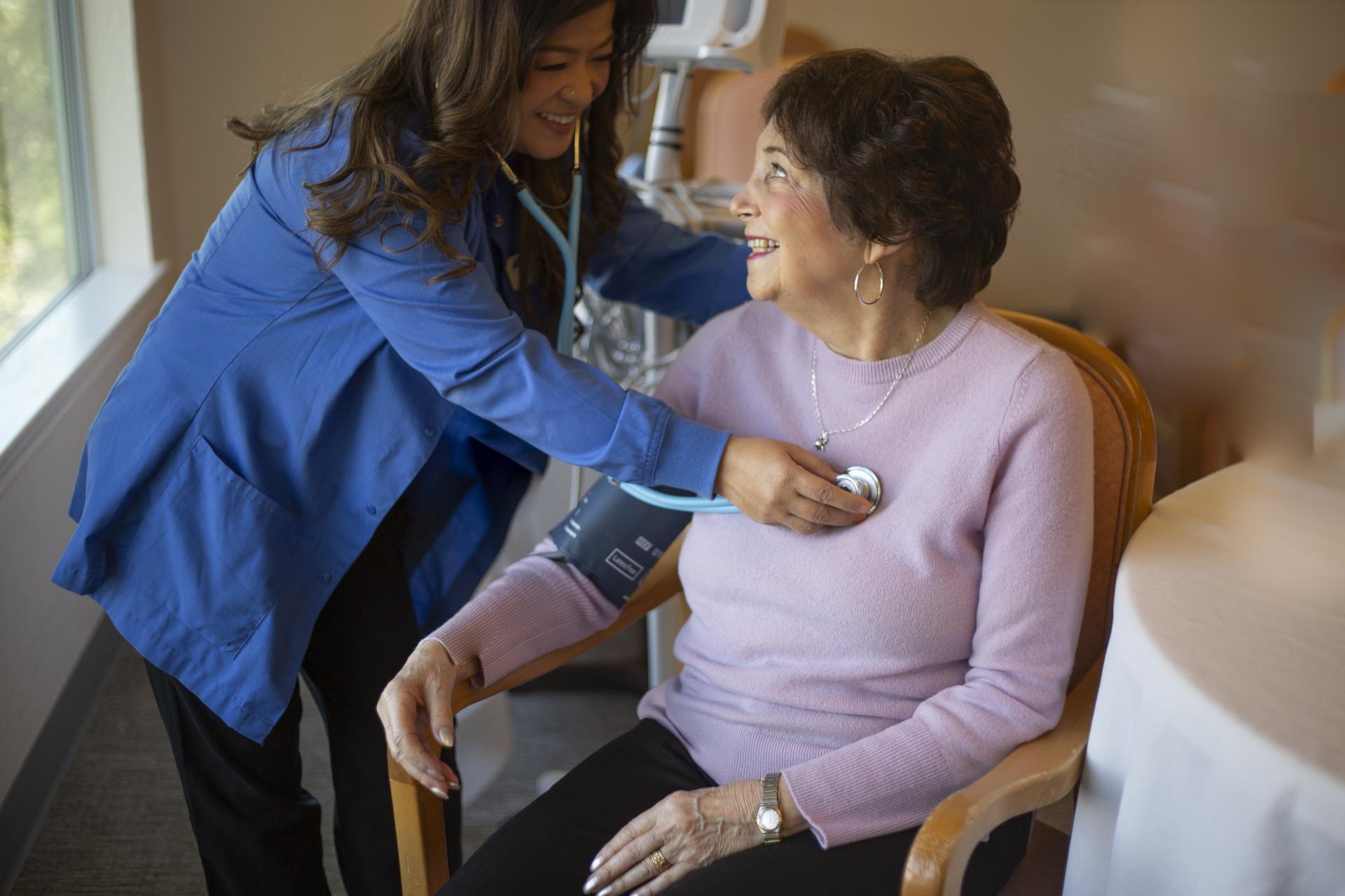 Medical person listening to woman's heart and taking her blood pressure
